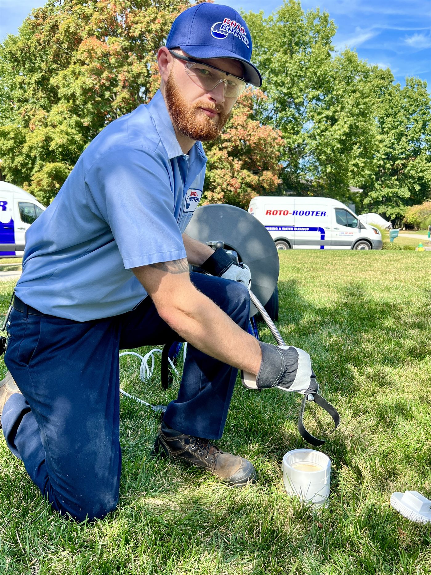 Roto-Rooter technician with a drain machine beside the service van