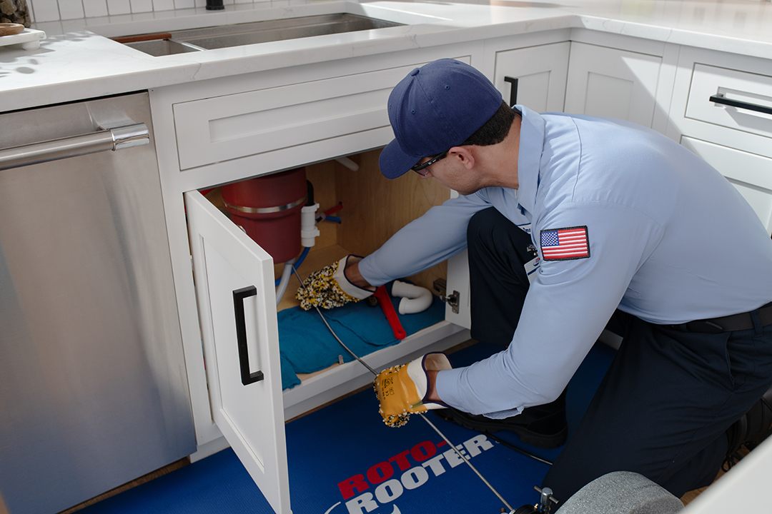 Roto-Rooter technician clearing a kitchen sink drain