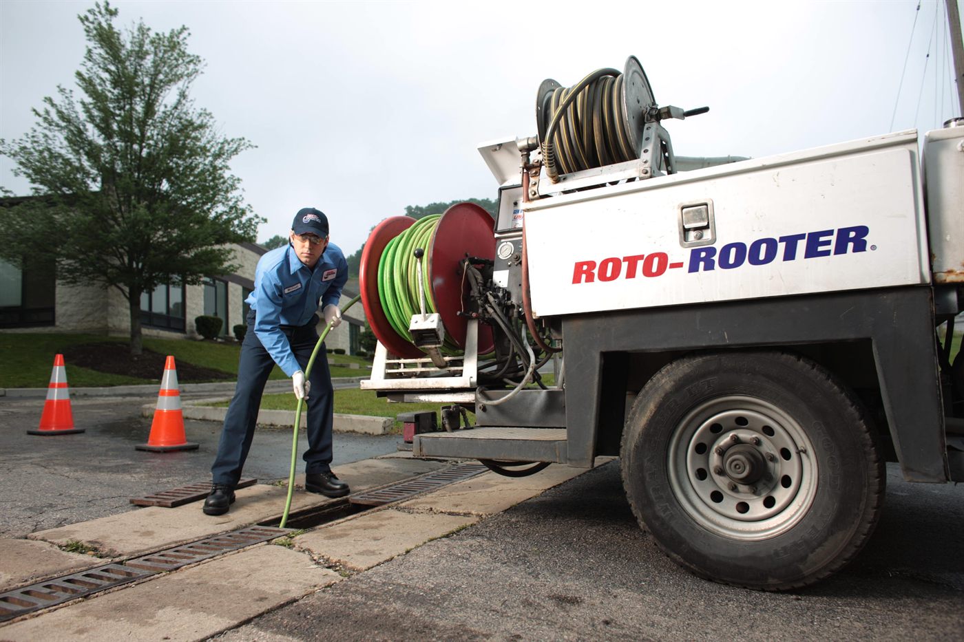 Roto-Rooter technician hydro jetting a line with a green hose