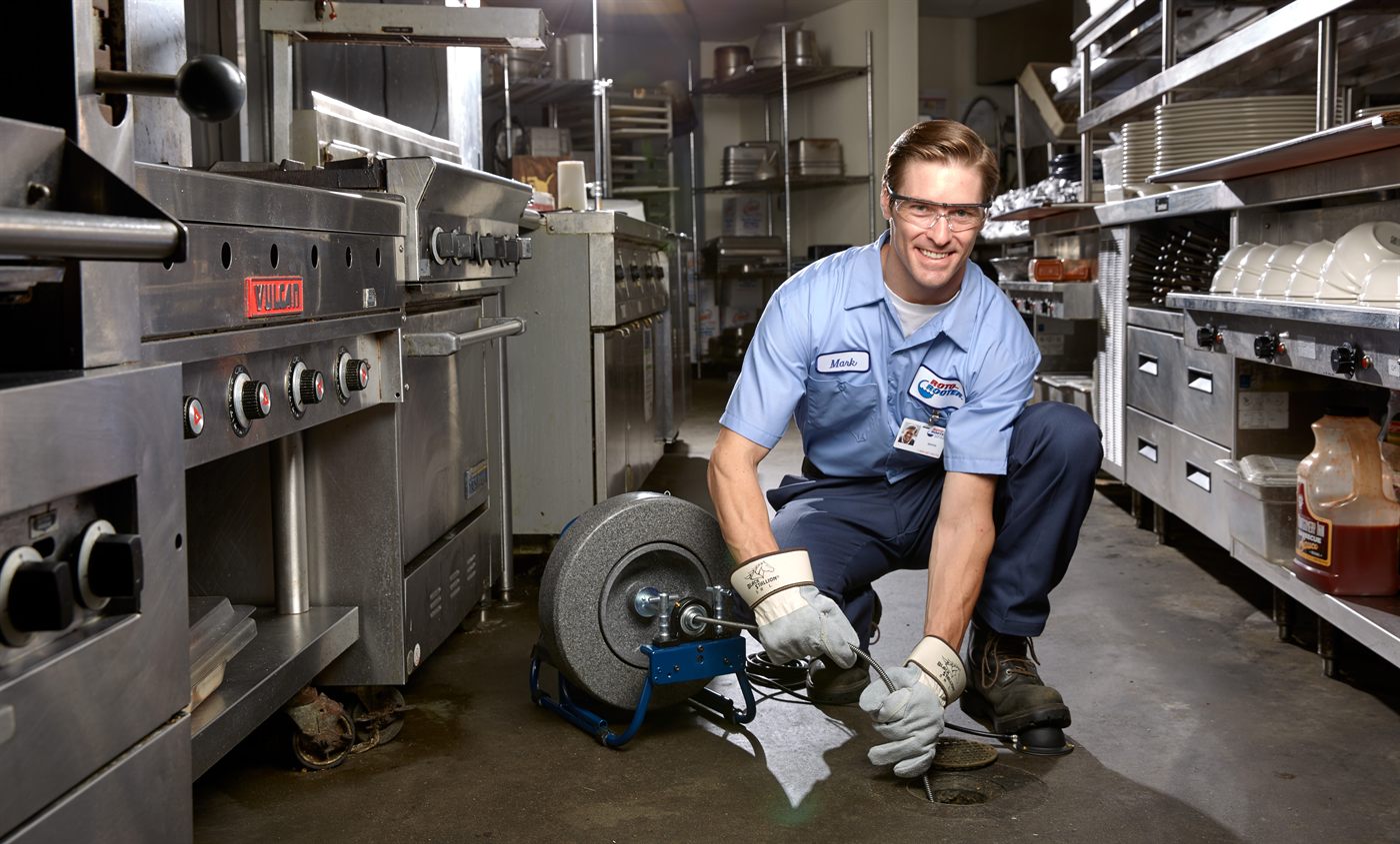 Roto-Rooter technician clearing a drain in a commercial kitchen