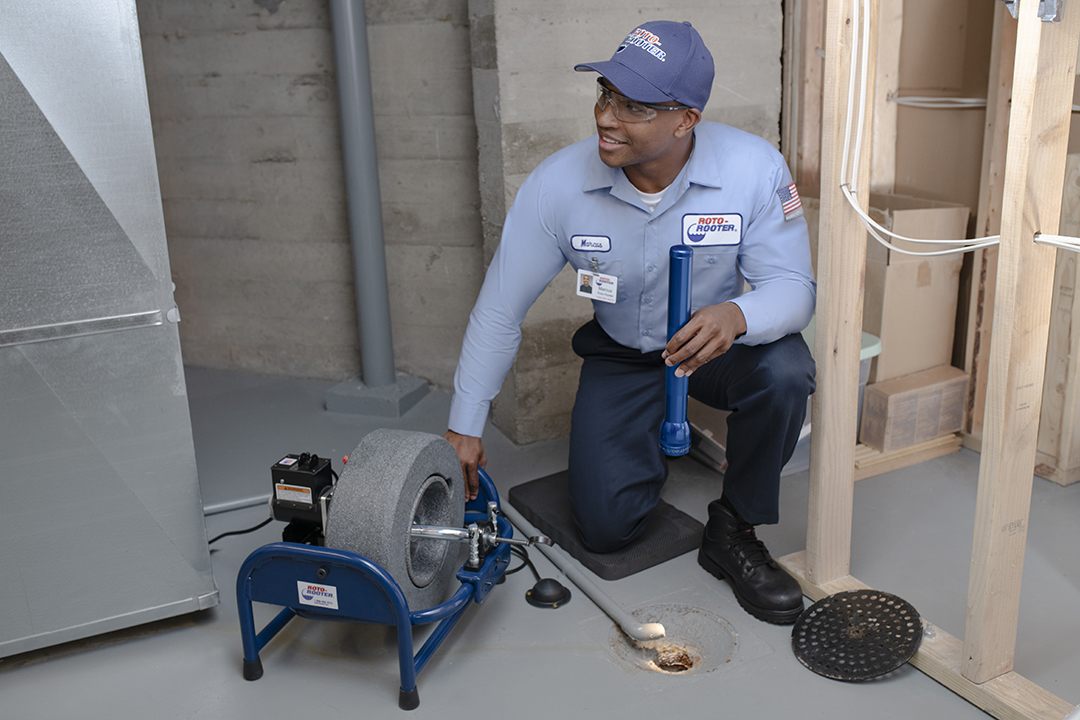 Roto-Rooter technician working on a basement floor drain